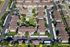 Aerial view of a picturesque apartment complex featuring lush green lawns, a sparkling swimming pool, and ample parking spaces surrounded by well-maintained residential buildings.