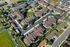 Aerial view of a modern apartment complex with lush green spaces, well-maintained landscaping, and ample parking.