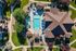Aerial view of a beautifully landscaped apartment complex featuring a sparkling blue pool, inviting lounge chairs, and vibrant green lawns.