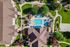 Aerial view of a vibrant apartment complex featuring a refreshing swimming pool, lush green landscaping, and inviting outdoor amenities, perfect for relaxation and recreation.