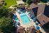 Luxurious aerial view of apartment complex featuring a stunning swimming pool, relaxing loungers, shaded areas with umbrellas, and a well-maintained garden perfect for outdoor enjoyment.