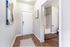 Inviting apartment entryway with elegant hardwood floors, leading to a modern bathroom featuring stylish decor.