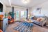Bright and inviting living room with modern decor, featuring a cozy gray sofa, vibrant orange chair, and stylish geometric rug.