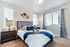 Bright and inviting bedroom with plush bed, modern decor, and natural light streaming through large windows.