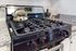 Modern kitchen with polished black stove and elegant kettle on granite countertop.