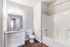 Elegant and contemporary bathroom featuring a sleek vanity with granite countertop, pristine bathtub, and modern chrome fixtures.