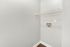 Bright utility room with sleek white walls, a mounted wire shelf, and convenient laundry hookups, perfect for modern functionality.