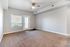 Bright living space with large window, plush carpet, and modern ceiling fan offering a welcoming atmosphere.