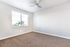 Bright and airy room featuring plush carpet, large window with natural light, and a sleek ceiling fan.