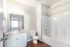 Bright bathroom featuring sleek white cabinetry, a granite countertop, and a modern tub-shower combo with elegant chrome fixtures.