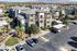Modern apartment complex featuring landscaped gardens, multiple levels, and ample parking, surrounded by stunning mountain views.