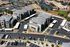 Modern apartment complex aerial view with landscaped grounds, spacious parking, and nearby recreational courts.