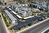 Aerial view of a modern apartment complex featuring stylish architecture, lush landscaping, and ample parking spaces, offering an ideal living environment.