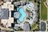 Aerial view of a luxurious apartment complex featuring a uniquely shaped swimming pool, relaxing lounging areas, and lush landscaping.