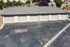 Charming row of garage units with a neatly paved driveway and lush greenery backdrop, offering ample parking and storage solutions.
