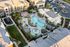 Aerial view of luxurious apartment complex featuring a resort-style pool, lush green landscaping, and modern buildings with private balconies.