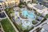 Aerial view of a luxurious apartment complex with a resort-style pool, palm trees, and cozy cabanas, offering a tropical oasis atmosphere.
