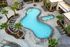 Luxurious apartment pool area with a uniquely shaped swimming pool, vibrant palm trees, and stylish poolside loungers under red umbrellas.