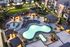Luxurious apartment complex showcasing an illuminated resort-style pool area surrounded by lush gardens and modern architecture.