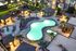 Luxurious apartment complex with a sparkling resort-style pool, elegant cabanas, and vibrant evening lighting.