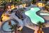 Luxurious resort-style pool area with palm trees, ambient lighting, and cozy lounge spaces for relaxation.
