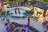 Stunning resort-style outdoor area featuring a sparkling pool, palm trees, modern lounge seating, and a chic gazebo with ambient lighting.