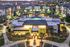 Stunning aerial view of a modern apartment complex at dusk, featuring a central illuminated pool, vibrant landscaping, and elegant architecture.