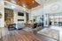 Luxurious living room with modern decor, featuring a sleek fireplace, elegant leather chairs, and abundant natural light through large glass doors.