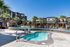 Luxurious apartment complex showcasing a stunning outdoor pool area with palm trees and lounging spaces under a clear blue sky.