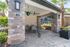 Charming outdoor patio with modern stone pillars, lush greenery, and vibrant hanging plants, perfect for relaxation.