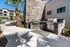 Charming outdoor grilling area with modern stone barbecue setup, surrounded by lush palm trees and a sunny patio, perfect for entertainment and relaxation.