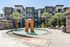 Luxurious apartment complex featuring a sparkling pool with unique rock formations, surrounded by palm trees and stylish lounge chairs, exuding a resort-style ambiance.