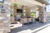 Inviting outdoor lounge featuring a cozy fireplace, modern ceiling fan, and elegant stone pillars, perfect for relaxation and entertainment.