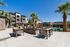Luxurious apartment complex with a pristine pool, stylish outdoor seating, and lush palm trees set against a clear blue sky.