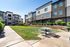 Modern apartment community with manicured landscaping, featuring vibrant greenery, picnic tables, and stylish multi-story buildings.