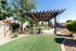 Charming outdoor area with a wooden pergola, lush greenery, and inviting seating, perfect for relaxation and gatherings.