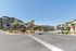 Charming apartment complex with modern architecture surrounded by palm trees and a tranquil fountain under a bright blue sky.