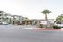 Inviting entrance to a modern apartment complex with palm trees and stone accents, featuring contemporary architecture and a welcoming atmosphere.