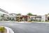 Modern apartment complex exterior with palm trees, stone facade, and inviting entrance set against a clear sky.