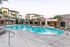 Luxurious apartment complex featuring a sparkling swimming pool surrounded by lush palm trees and modern architecture.