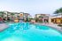 Luxurious apartment complex with a stunning resort-style pool, surrounded by palm trees and modern architecture.