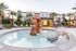 Charming outdoor pool area with unique rock sculpture, surrounded by sun loungers and shaded seating, perfect for relaxation.
