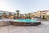 Luxurious apartment complex with a sparkling pool surrounded by palm trees and inviting modern architecture.