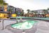 Modern apartment complex with luxurious pool and spa area, surrounded by palm trees and stylish seating under a serene evening sky.