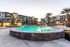 Modern apartment complex with palm trees and a stunning illuminated pool, offering a luxurious lifestyle.