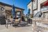 Charming outdoor patio with stone accents, featuring elegant dining tables and a modern grill, perfect for alfresco living.