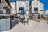 Modern townhomes with stylish stone facades, featuring an inviting outdoor patio with seating and a barbecue area.