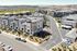 Charming hillside apartment complex with modern three-story townhomes, lush landscaping, and ample parking spaces, boasting stunning mountain views and clear blue skies.