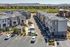 Modern apartment complex with stylish gray buildings, lush landscaping, and ample parking, set against a scenic mountain backdrop.