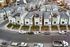 Aerial view of modern townhouse complex with stylish architecture, neatly landscaped gardens, and convenient parking spaces on a vibrant, well-maintained street.